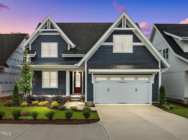 view of front of property with driveway, a shingled roof, and a garage