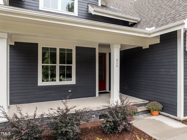 entrance to property with a shingled roof and covered porch