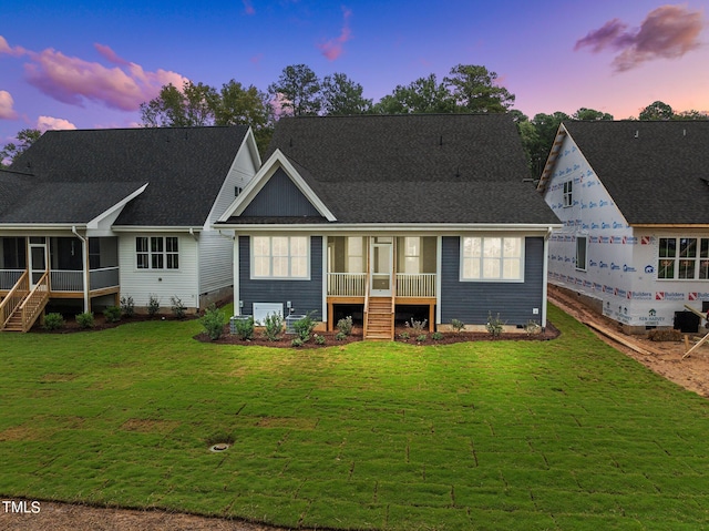 back of property at dusk featuring a sunroom, a yard, stairway, and crawl space