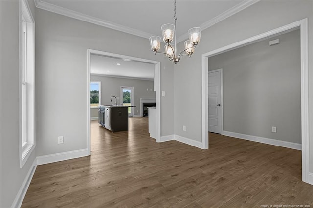 unfurnished dining area with ornamental molding, a sink, dark wood finished floors, and baseboards