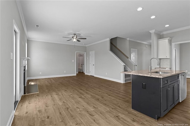 kitchen featuring baseboards, white cabinets, a kitchen island, wood finished floors, and a sink