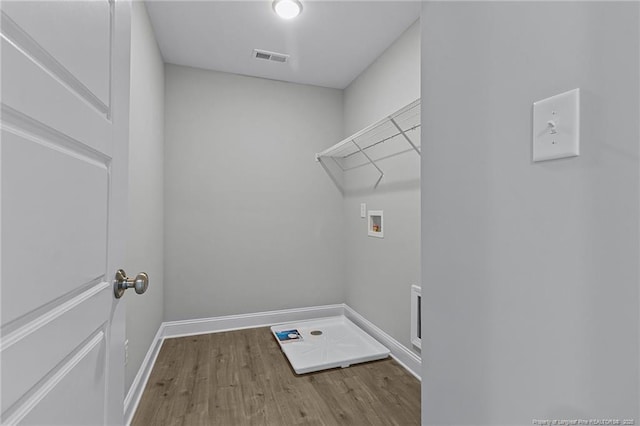 washroom with hookup for a washing machine, laundry area, wood finished floors, visible vents, and baseboards