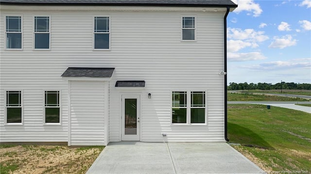 rear view of property with a shingled roof and a patio