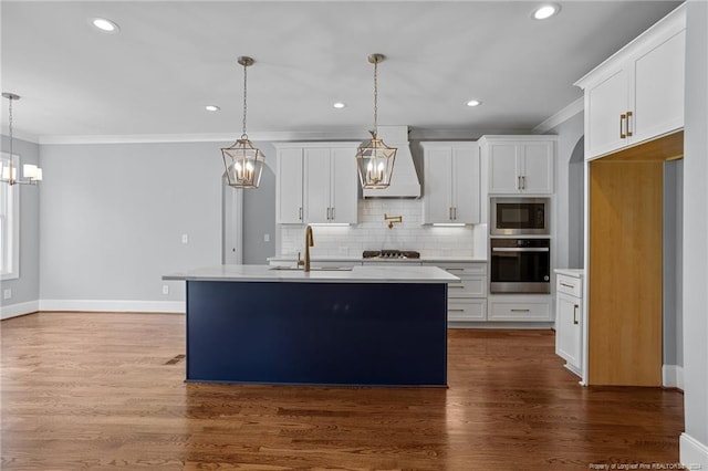 kitchen featuring white cabinets, stainless steel appliances, premium range hood, and a center island with sink