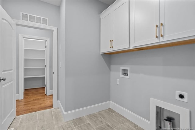 washroom featuring electric dryer hookup, cabinets, hookup for a washing machine, and light hardwood / wood-style flooring