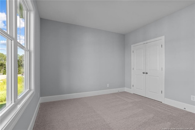 unfurnished bedroom featuring light carpet and a closet