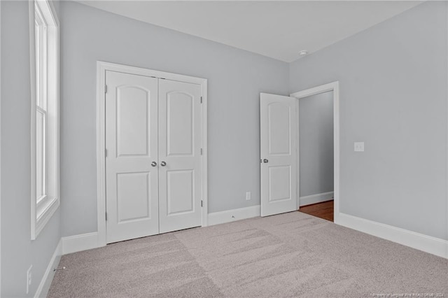 unfurnished bedroom with light colored carpet and a closet