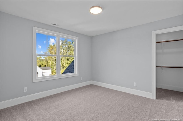 unfurnished bedroom with carpet flooring, a spacious closet, and a closet