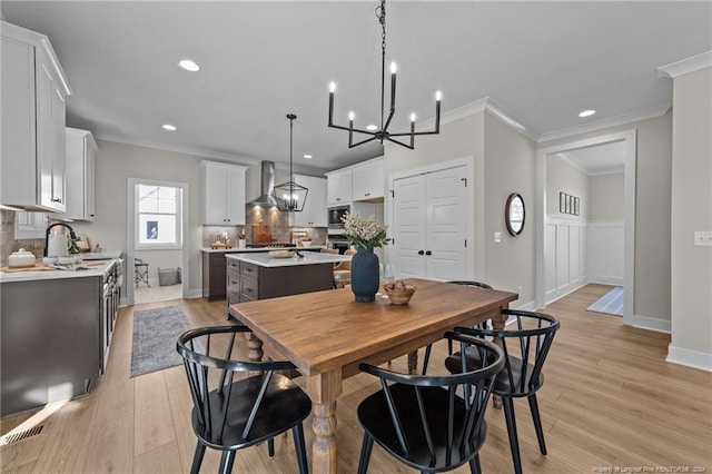 dining space featuring an inviting chandelier, crown molding, and light hardwood / wood-style flooring