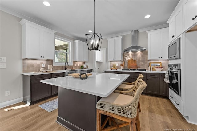 kitchen with white cabinets, a center island, oven, and wall chimney range hood