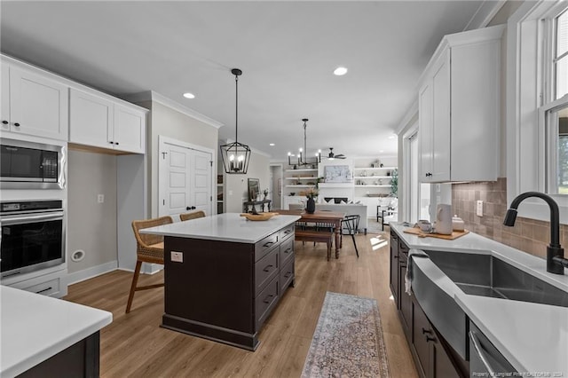 kitchen featuring stainless steel appliances, sink, decorative light fixtures, white cabinets, and a kitchen island