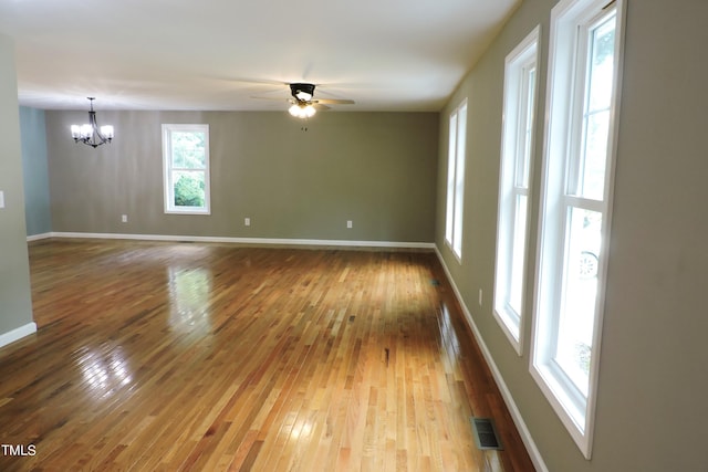 unfurnished room with ceiling fan with notable chandelier and wood-type flooring