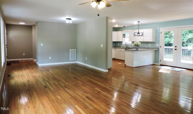 unfurnished living room with ceiling fan, french doors, and dark hardwood / wood-style flooring