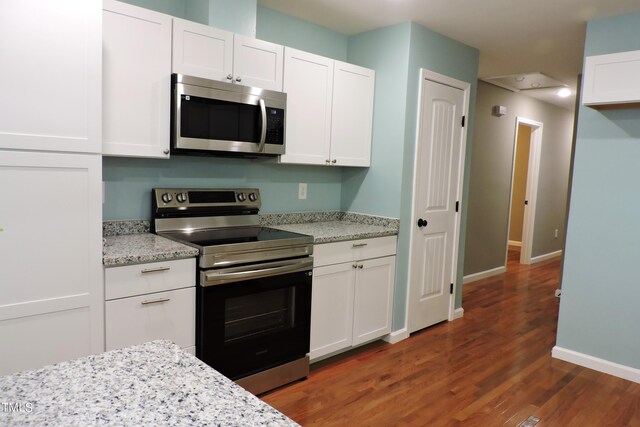 kitchen with white cabinetry, dark wood-type flooring, light stone counters, and appliances with stainless steel finishes