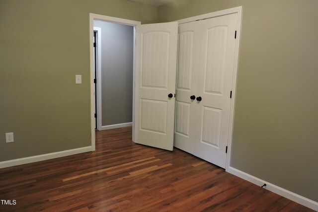 unfurnished bedroom with dark hardwood / wood-style floors and a closet