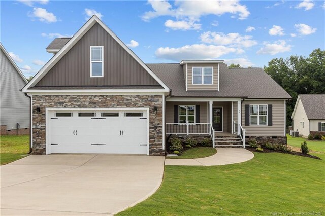 craftsman inspired home with cooling unit, a garage, and a front lawn