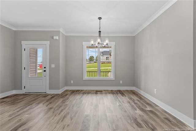 unfurnished dining area featuring ornamental molding, an inviting chandelier, wood finished floors, and baseboards