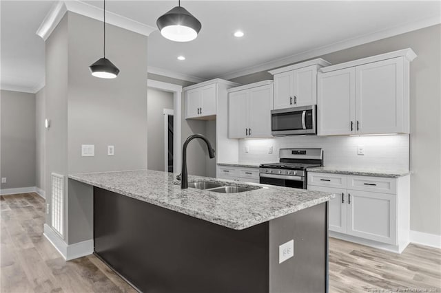 kitchen featuring appliances with stainless steel finishes, a sink, decorative light fixtures, and white cabinets