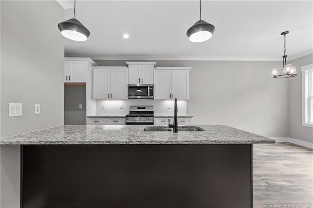 kitchen with white cabinets, light stone counters, decorative light fixtures, stainless steel appliances, and a sink