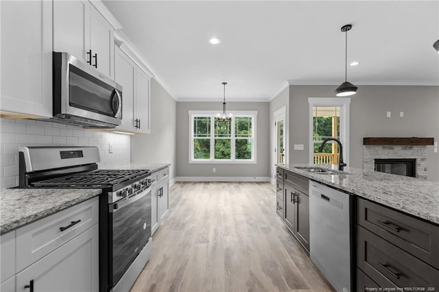 kitchen featuring stainless steel appliances, light stone countertops, white cabinetry, and decorative light fixtures