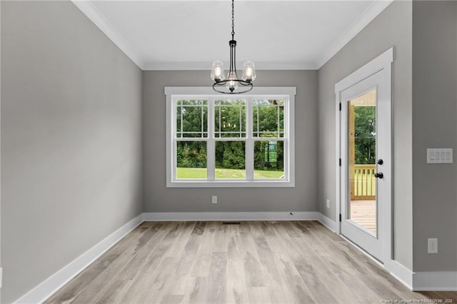 unfurnished dining area featuring a notable chandelier, crown molding, light wood finished floors, and baseboards