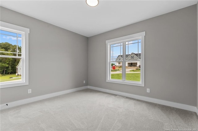 carpeted empty room with visible vents, plenty of natural light, and baseboards