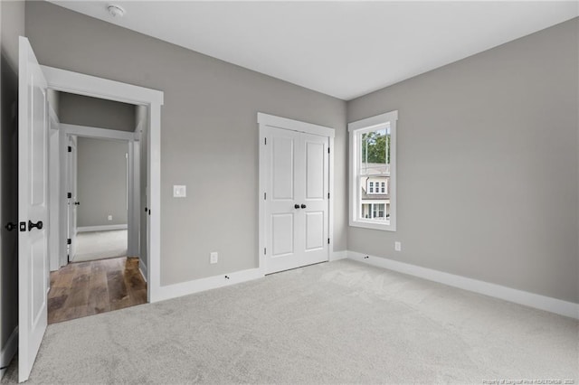 unfurnished bedroom featuring light carpet, a closet, and baseboards