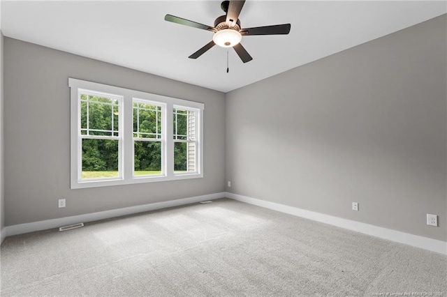 carpeted spare room featuring ceiling fan, visible vents, and baseboards