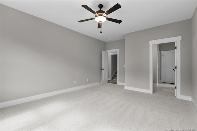 unfurnished bedroom featuring a ceiling fan, light colored carpet, and baseboards