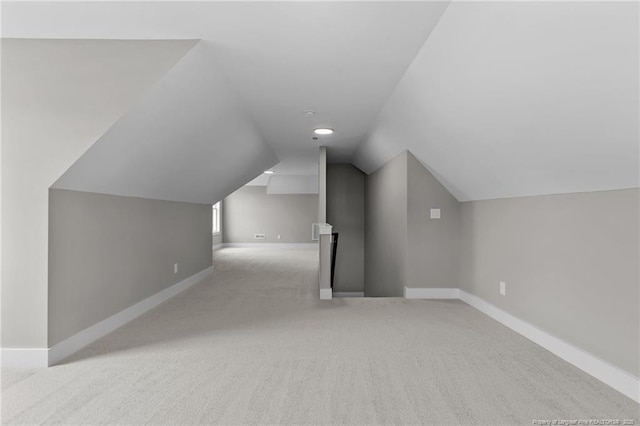 bonus room featuring baseboards, vaulted ceiling, and light colored carpet