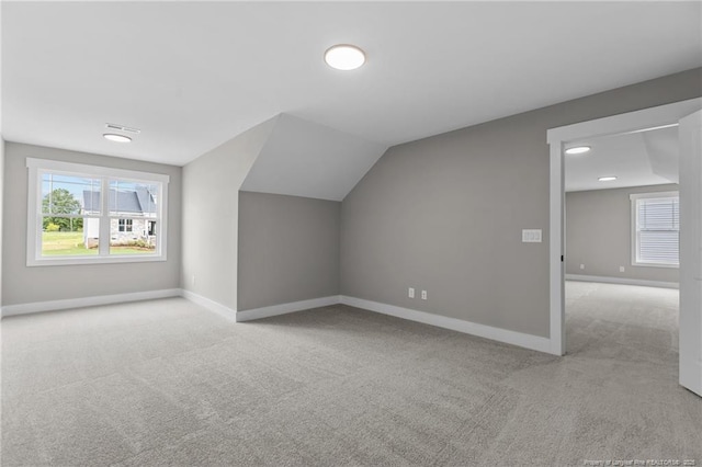 additional living space with light carpet, lofted ceiling, and baseboards