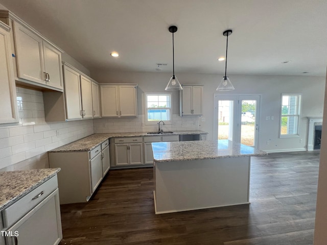 kitchen with pendant lighting, white cabinetry, a center island, sink, and dark wood-type flooring