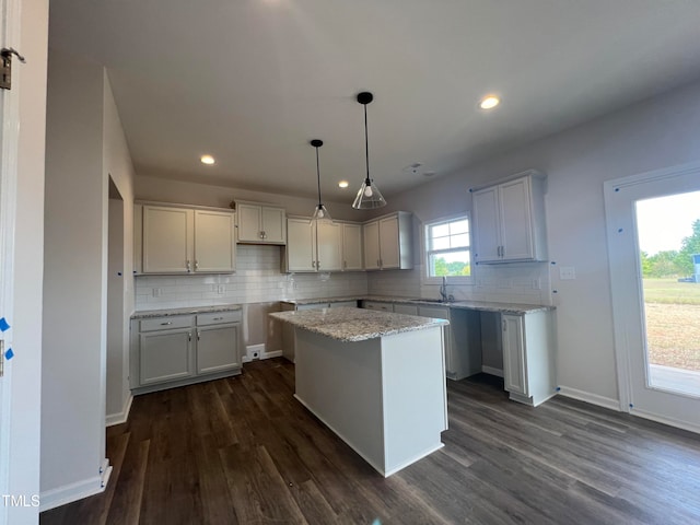 kitchen featuring a center island, backsplash, hanging light fixtures, and dark hardwood / wood-style flooring