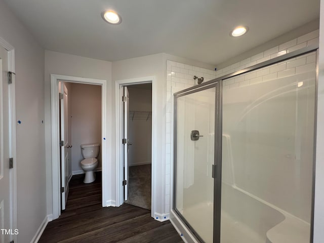 bathroom featuring hardwood / wood-style floors, toilet, and a shower with shower door