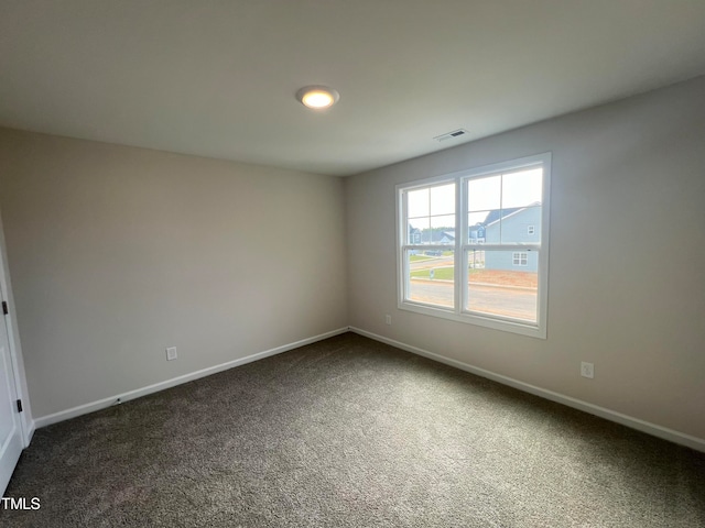 spare room featuring dark carpet