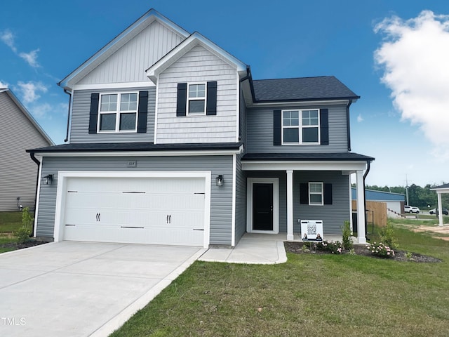 traditional-style home with a front lawn, concrete driveway, an attached garage, covered porch, and roof with shingles