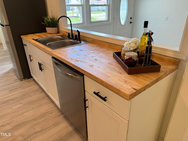 kitchen with light wood-type flooring, sink, and wooden counters