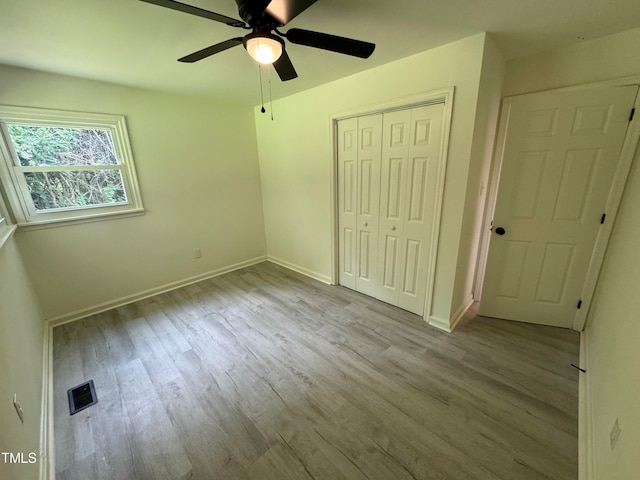 unfurnished bedroom featuring light hardwood / wood-style flooring, ceiling fan, and a closet