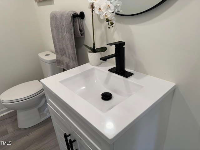 bathroom with hardwood / wood-style floors, toilet, and vanity