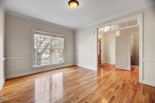 empty room featuring light wood-type flooring and ornamental molding