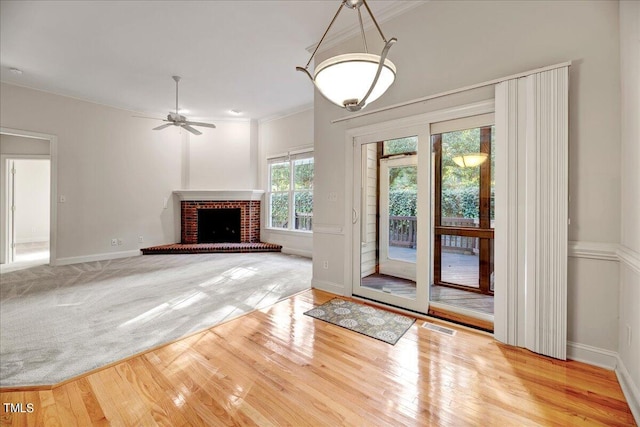 unfurnished living room with wood-type flooring, a brick fireplace, and ceiling fan