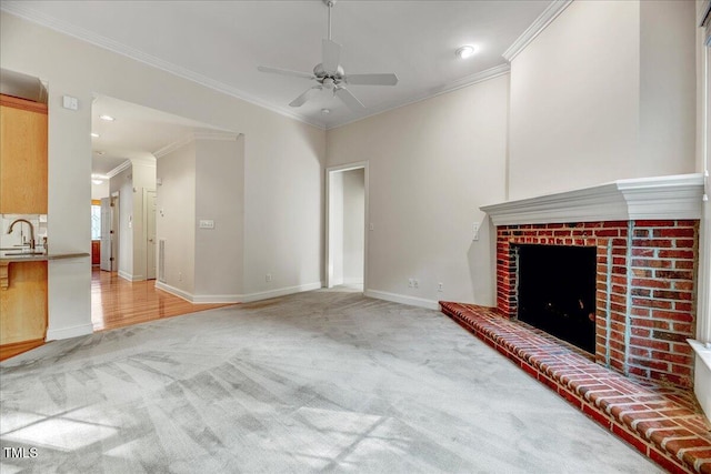 unfurnished living room featuring ceiling fan, light carpet, sink, a fireplace, and ornamental molding