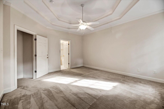 unfurnished bedroom featuring ceiling fan, light colored carpet, a raised ceiling, and ornamental molding