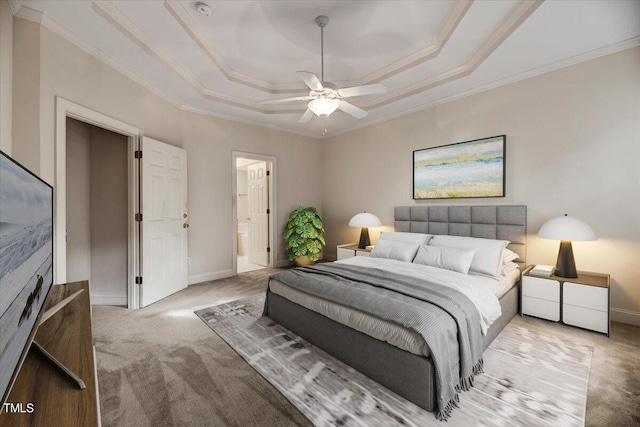 carpeted bedroom featuring ornamental molding, ceiling fan, a tray ceiling, and connected bathroom