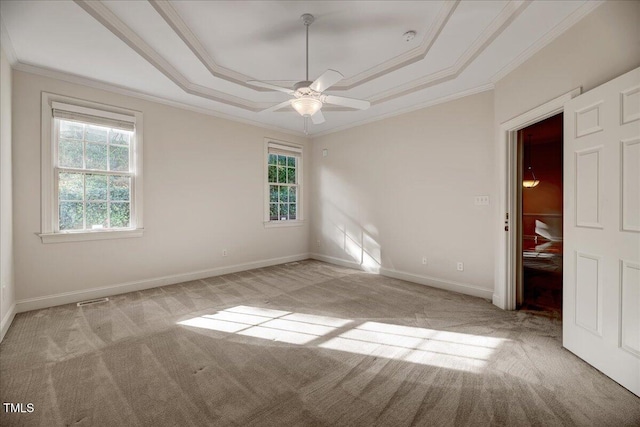 empty room with light carpet, a raised ceiling, ornamental molding, and ceiling fan