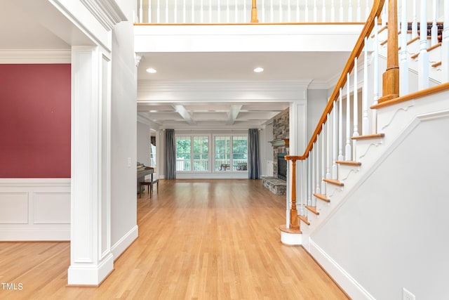 entrance foyer with ornate columns, beamed ceiling, light hardwood / wood-style floors, crown molding, and coffered ceiling