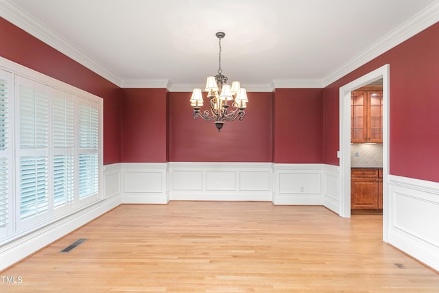 unfurnished dining area featuring light hardwood / wood-style floors, a notable chandelier, and ornamental molding