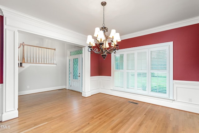 spare room featuring hardwood / wood-style flooring, a chandelier, and ornamental molding