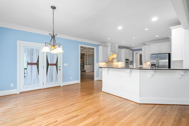 kitchen featuring a kitchen breakfast bar, white cabinetry, hanging light fixtures, and appliances with stainless steel finishes