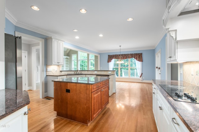 kitchen with white cabinets, a kitchen island, light wood-type flooring, and sink